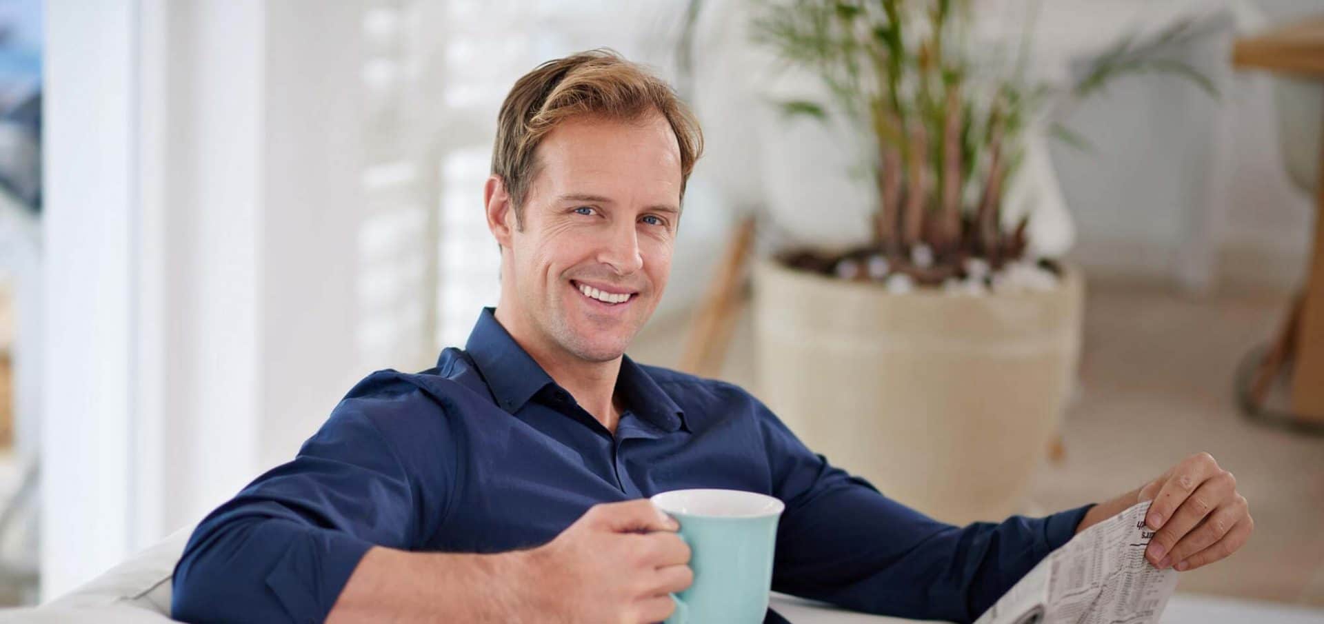 Happy man drinks coffee after hair transplant at HSI